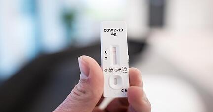 Ein Mann hält einen Corona-Schnelltest in der Hand.
