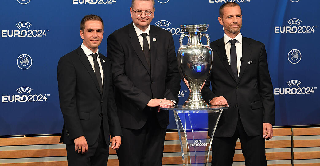 DFB-Präsident Reinhard Grindel (Mitte) und EM-Botschafter Philipp Lahm (links) der deutschen Delegation und Aleksander Ceferin, Präsident der Uefa, stehen neben dem EM-Pokal während der Bekanntgabe-Zeremonie zur Ausrichtung der Fußball-Europameisterschaft 2024.