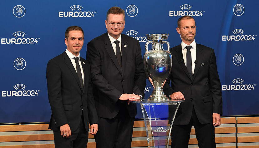 DFB-Präsident Reinhard Grindel (Mitte) und EM-Botschafter Philipp Lahm (links) der deutschen Delegation und Aleksander Ceferin, Präsident der Uefa, stehen neben dem EM-Pokal während der Bekanntgabe-Zeremonie zur Ausrichtung der Fußball-Europameisterschaft 2024.
