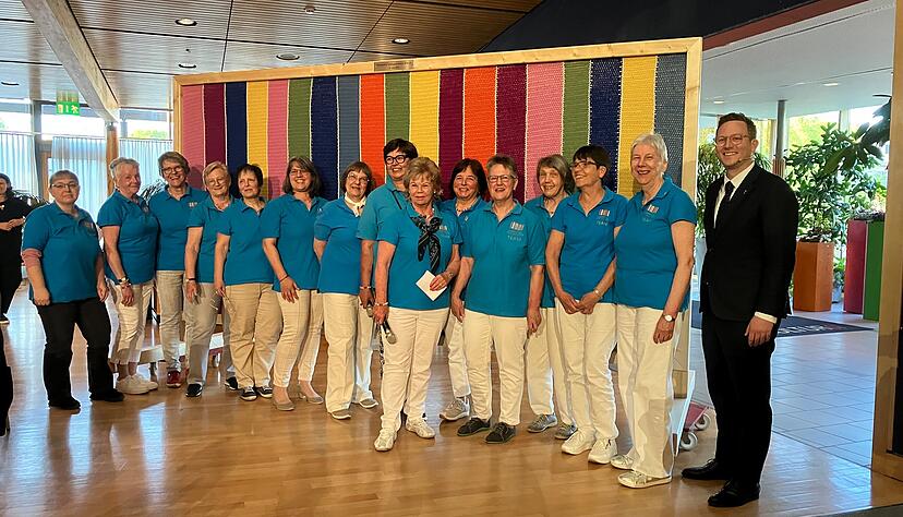 16 Kreativfrauen vom Laga-Freundeskreis haben 80 Kn&auml;uel Wolle zu einem gro&szlig;en Bild mit bunten Stelen verh&auml;kelt.