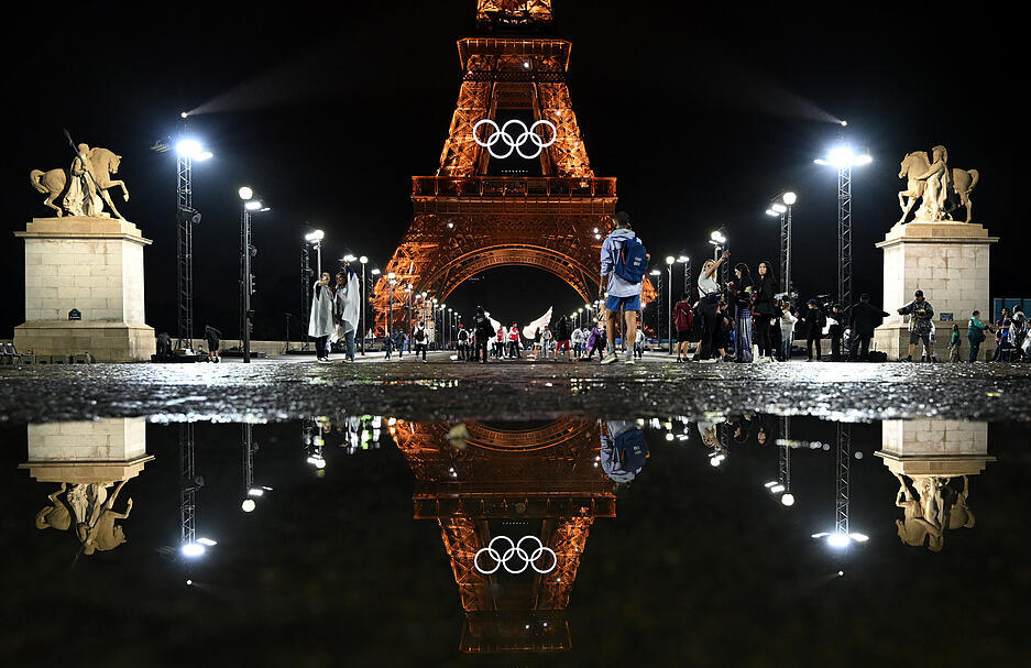 Der beleuchtete Eiffelturm mit den Olympischen Ringen spiegelt sich in einer Pfütze bei der Eröffnungsfeier in Paris.