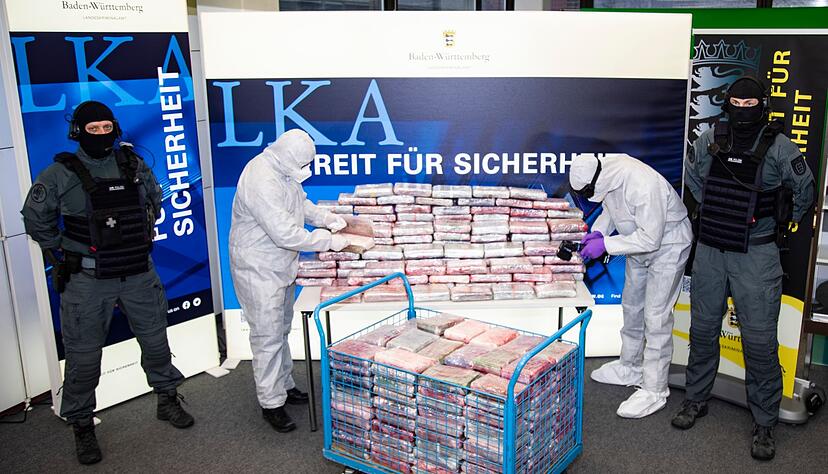 Polizeibeamte stehen neben einem Berg an Kokain-Paketen. Polizeibeamte stehen neben einem Berg an Kokain-Paketen.