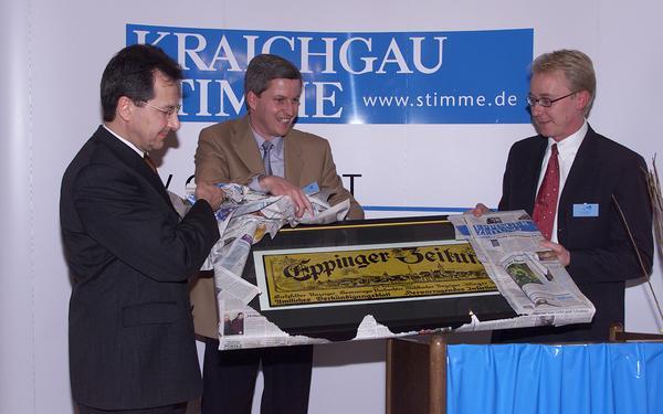 16. Februar 2001: Die beiden Geschäftsführer des Medienunternehmens Heilbronner Stimme,  Bernd Herzberger (l) und Tilmann Distelbarth (r), überreichen dem früheren Leiter der Außenredaktion und heutigen Chefredakteur der Heilbronner Stimme/Kraichgau Stimme/Hohenloher Zeitung Uwe Heer beim Festakt ein historisches Schild der Eppinger Zeitung. Von 1899 bis 1971 war die Heimatzeitung im Verlag der Eppinger Familie Lutz herausgegeben worden. Seit 1972 erscheint die Eppinger Zeitung als eine von 10 HSt-Lokalausgaben.