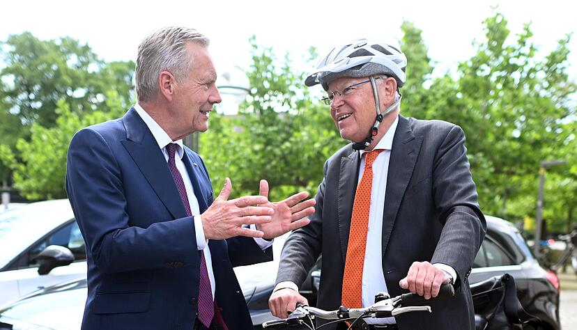 Mit Helm und Fahrrad kommt Stephan Weil (r) zur Wahl, bei der auch Christian Wulff zu Gast ist.
