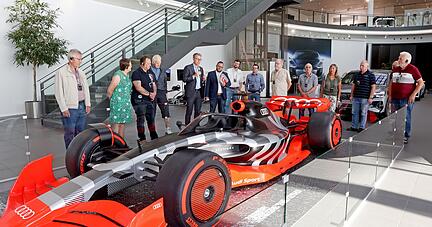 Neckarsulms Werkleiter Fred Schulze (Mitte mit Mikrofon) hat den Teilnehmern auch das Formel 1-Showcar gezeigt und viel zum Standort erzählt.
Foto: Ralf Seidel