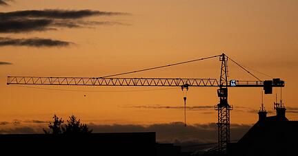 Ein Baukran zeichnet sich in Dresden bei Sonnenaufgang als Silhouette ab.