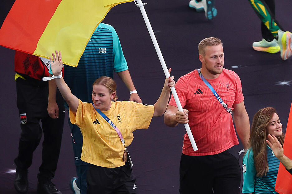 Triathletin Laura Lindemann und der Renn-Kanute Max Rendschmidt tragen bei der Schlussfeier die deutsche Fahne ins Stadion.