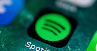 Die App des Musikdienstes Spotify wird auf dem Display eines iPhone angezeigt.