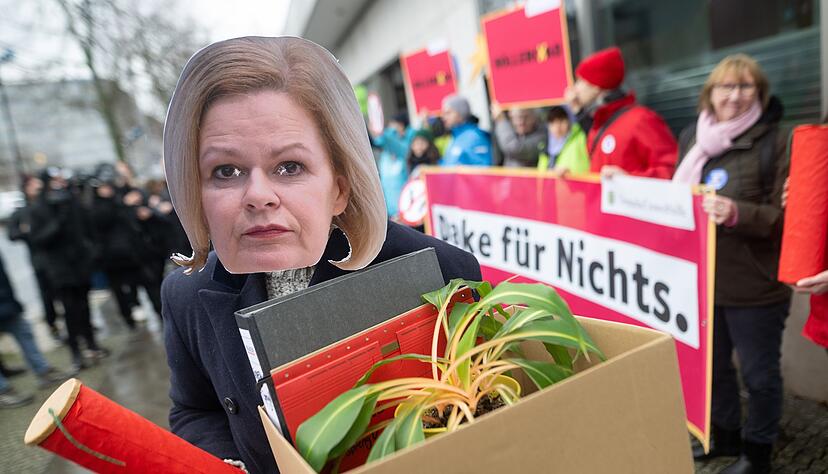 Eine Aktivistin demonstriert mit einer Maske von Bundesinnenministerin Nancy Faeser.