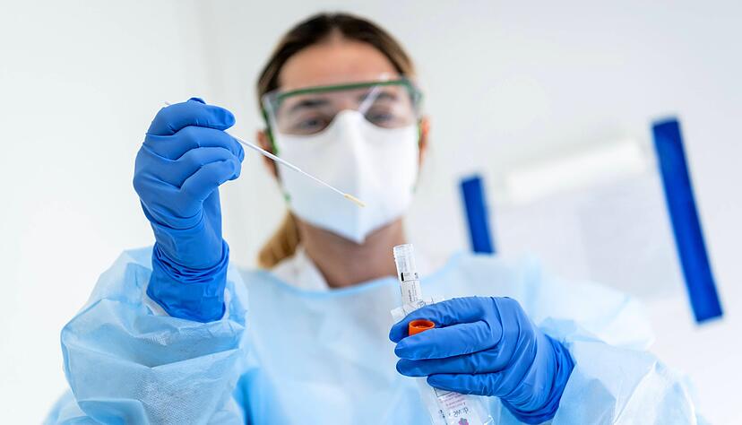 Labore haben alle H&auml;nde voll zu tun. Eine Krankenschwester steckt auf diesem Themenbild den Abstrich eines Patienten in einen Beh&auml;lter. 
Foto: dpa