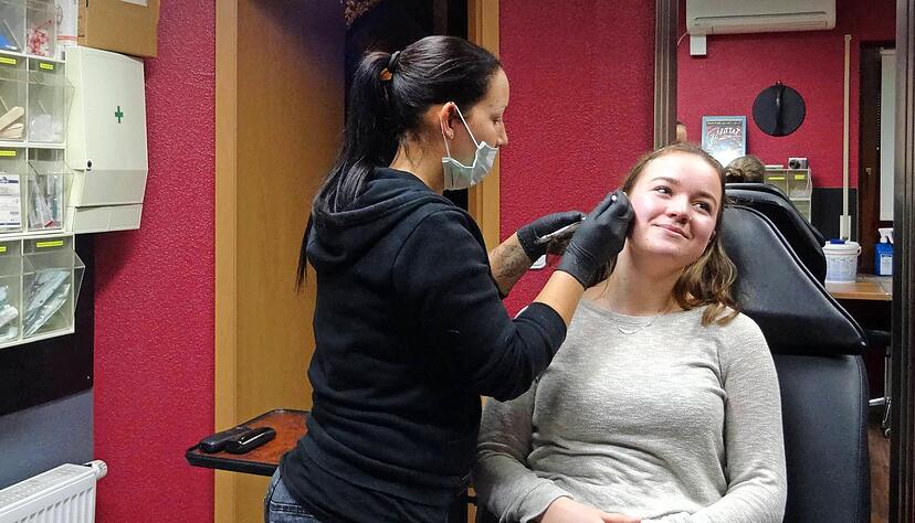 Da braucht man schon Vertrauen in die Piercerin: Silke Dold (links) sticht Barbara Beck das Piercing durch die Ohrmuschel. Für die junge Frau ist es bereits das zwölfte Schmuckstück, das ihr durch die Haut gestochen wird. 
Foto: privat