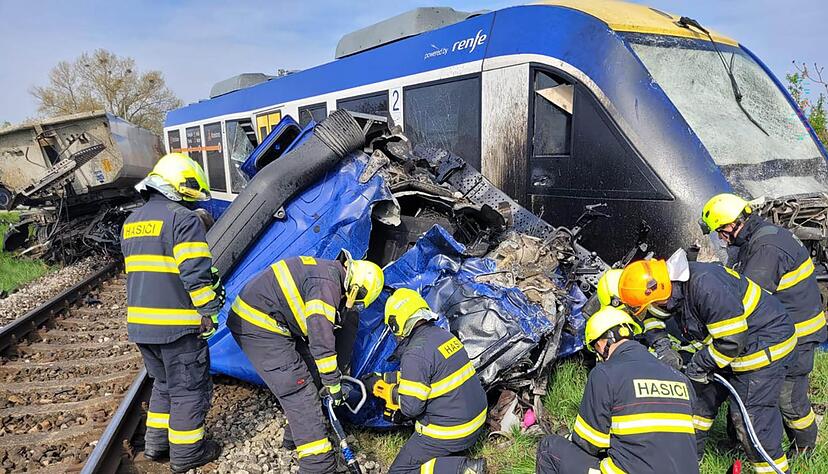 Feuerwehrleute arbeiten am Ungl&uuml;cksort, wo ein Personenzug und ein Lastwagen zusammengesto&szlig;en sind. Bei dem Ungl&uuml;ck kam eine Person ums Leben, 21 Menschen wurden verletzt.