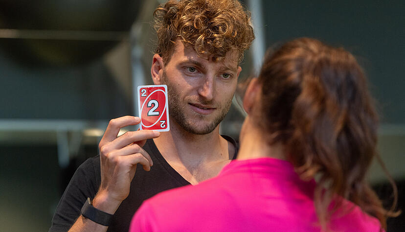 Athletin Lorena Schädel fixiert mit nach rechts geneigtem Kopf eine Uno-Karte. Athletin Lorena Schädel fixiert mit nach rechts geneigtem Kopf eine Uno-Karte.