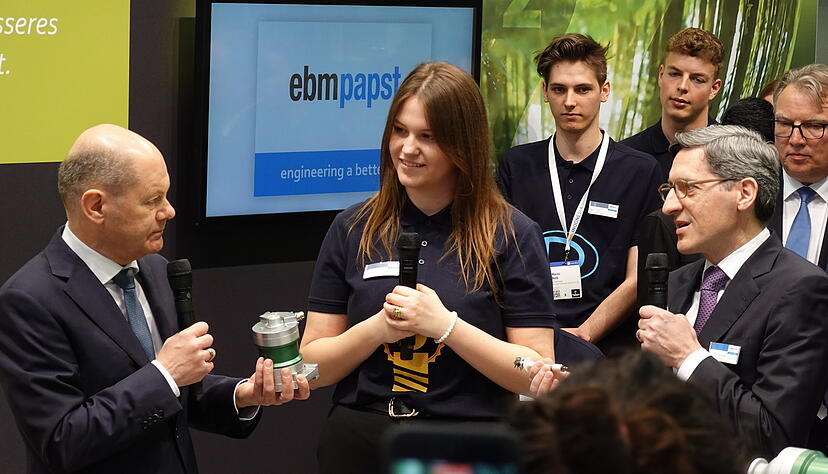 Bundeskanzler Olaf Scholz lässt sich von EBM-Papst-Studentin Melanie Bildhoff erläutern, was das Besondere an den Kompressoren ist. Rechts EBM-Papst-Chef Klaus Geißdörfer. Bundeskanzler Olaf Scholz lässt sich von EBM-Papst-Studentin Melanie Bildhoff erläutern, was das Besondere an den Kompressoren ist. Rechts EBM-Papst-Chef Klaus Geißdörfer.