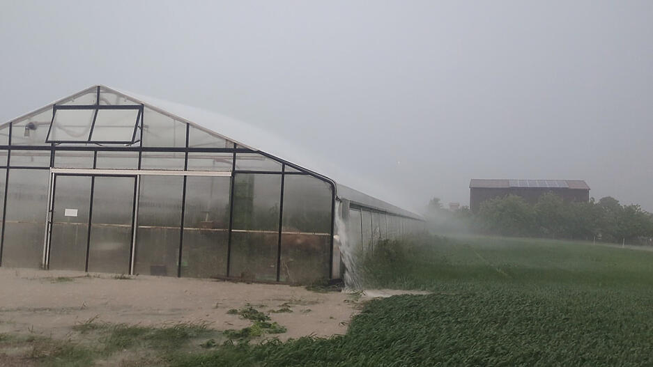 Regenwasser läuft bei einem starken Gewitter vom Dach eines Gewächshauses. Regenwasser läuft bei einem starken Gewitter vom Dach eines Gewächshauses.