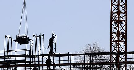 Handwerker arbeiten am Neubau eines Mehrfamilienhauses an einem Bauger&uuml;st. Der Staat will Neubauten f&ouml;rdern.