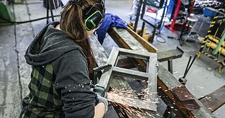 Eine Auszubildende zum Metallbauer arbeitet mit einem Schleifger&auml;t.