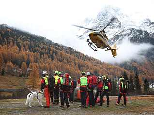 Ein Hubschrauber der Bergrettung landet vor Bergrettern.