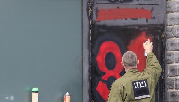 Ein Polizist übersprüht am Clubhaus die Ziffer 81, die für den achten und ersten Buchstaben im Alphabet - und damit die Abkürzung von Hells Angels steht. Foto: Florian Schuh