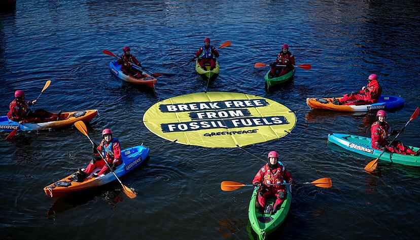 Greenpeace fordert bei einer Aktion am Veranstaltungsort die Abkehr von fossilen Energien.