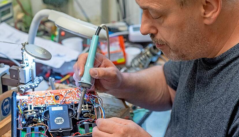 Mitarbeiter Ralf Wenzel wechselt den Akku einer Fernsteuerung eines Modellfahrzeugs.