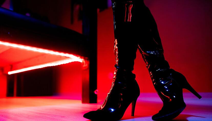 Eine Prostituierte steht vor der roten Beleuchtung unter einem Bett in einem Studio. Eine Prostituierte steht vor der roten Beleuchtung unter einem Bett in einem Studio.