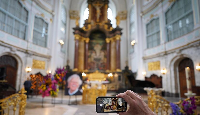 Ein Besucher macht zu Beginn der Trauerfeier ein Foto mit einem Smartphone.