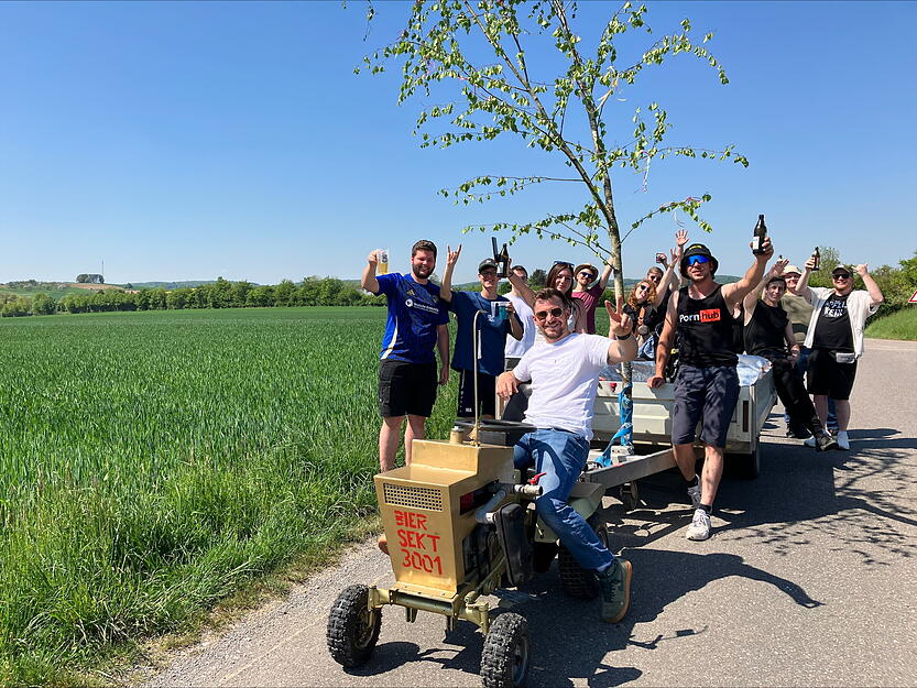 Mit einem goldenen Rasenmähertraktor ist die Gruppe von Schwabbach Richtung Pfedelbach unterwegs. Gut, dass kaltes Bier dabei ist.