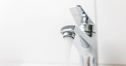 Wasser fließt durch einen geöffneten Hahn. Wasser fließt durch einen geöffneten Hahn.