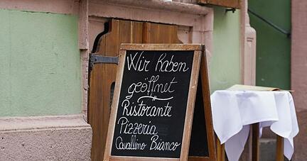 Ein Schild mit der Aufschrift ?Wir haben geöffnet? steht vor einem Restaurant in der Innenstadt.