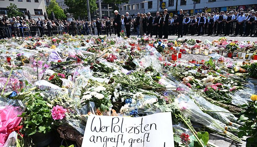 Blumen und Kerzen liegen bei einer Gedenkminute auf dem Marktplatz in Mannheim zum Gedenken an einen getöteten Polizisten. Blumen und Kerzen liegen bei einer Gedenkminute auf dem Marktplatz in Mannheim zum Gedenken an einen getöteten Polizisten.