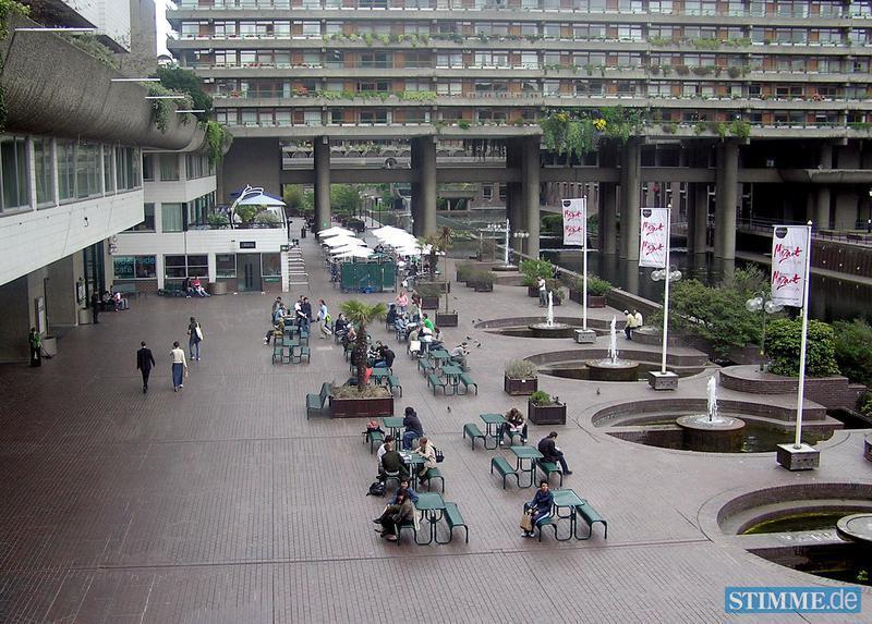 Das Quartier Barbican ist eines der bekanntesten und gr&ouml;&szlig;ten Beispiele f&uuml;r britische Architektur aus der Epoche des Brutalismus. Das Gebiet mitten in der Londoner City wurde im Zweiten Weltkrieg durch Angriffe der deutschen Luftwaffe zerst&ouml;rt. In den 1950er Jahren gab es einen Architektenwettbewerb f&uuml;r seine &Uuml;berbauung. 

Aus dem Siegerentwurf, einer Vision f&uuml;r das urbane Leben der Zukunft, entstand in den 1960er und 70er Jahren eine der gr&ouml;&szlig;ten Wohnsiedlungen Londons, der Barbican Estate. Au&szlig;erdem ein Kulturzentrum, das Barbican Center, in dem unter anderem die Royal Shakespeare Company beheimatet ist. "In London, wo der Wohnungsdruck so gro&szlig; ist, ist das ein gutes Beispiel f&uuml;r gelungene verdichtete Architektur aus dieser Zeit", sagt Anette Busse vom Fachbereich Architektur des Karlsruher Instituts f&uuml;r Technologie (KIT). 

Die Siedlung sei hochwertig angelegt und gepflegt. Die Wohngeb&auml;ude sind um einen See herum gruppiert, mit viel Gr&uuml;nraum. Das Problem in London hei&szlig;t Gentrifizierung: Inzwischen sei Wohnen im Barbican-Quartier fast nur noch f&uuml;r die gut verdienende Oberschicht finanzierbar.