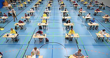 Abitur mit Corona-Auflagen: Jugendliche sitzen während der Deutsch-Prüfung mit vorgeschriebenen Abstand zueinander in einer Sporthalle.

Foto: dpa