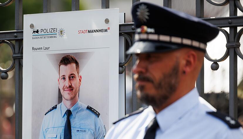 Ein Polizist steht neben einer Gedenktafel f&uuml;r Rouven Laur.