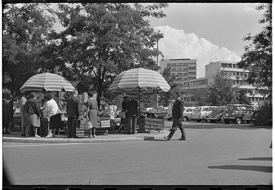 Juli 1964: Marktstände stehen am Rande der Autostellplatzflächen. Mittlerweile sind die Bäume gewachsen und spenden etwas Schatten.