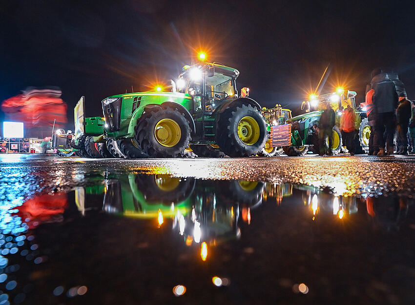 Viele Traktoren von Landwirten stehen am frühen Morgen auf einem Parkplatz, um sich für ihre Fahrt in Richtung Berlin zu sammeln.