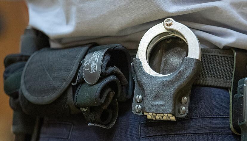Handschellen stecken in der Gürtelhalterung eines Justizbeamten. Handschellen stecken in der Gürtelhalterung eines Justizbeamten.