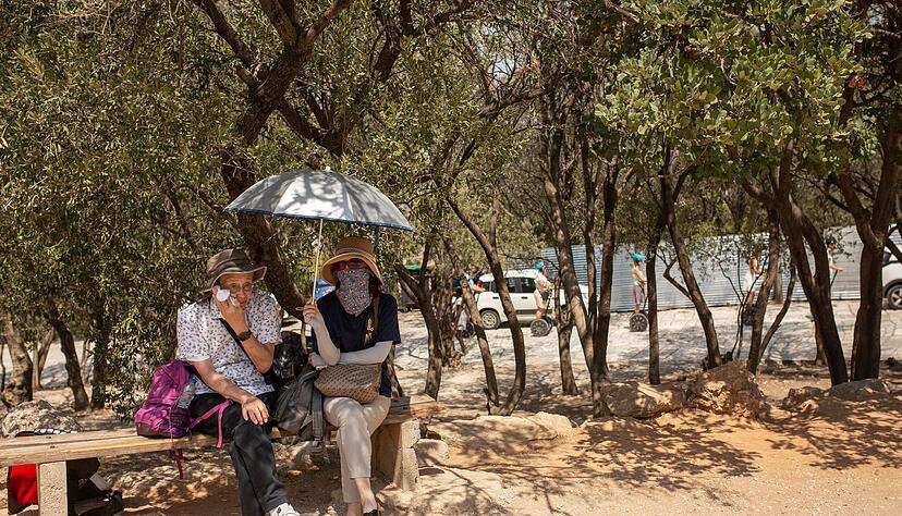 Touristen sitzen unter Bäumen am Eingang der Akropolis in Athen. Touristen sitzen unter Bäumen am Eingang der Akropolis in Athen.