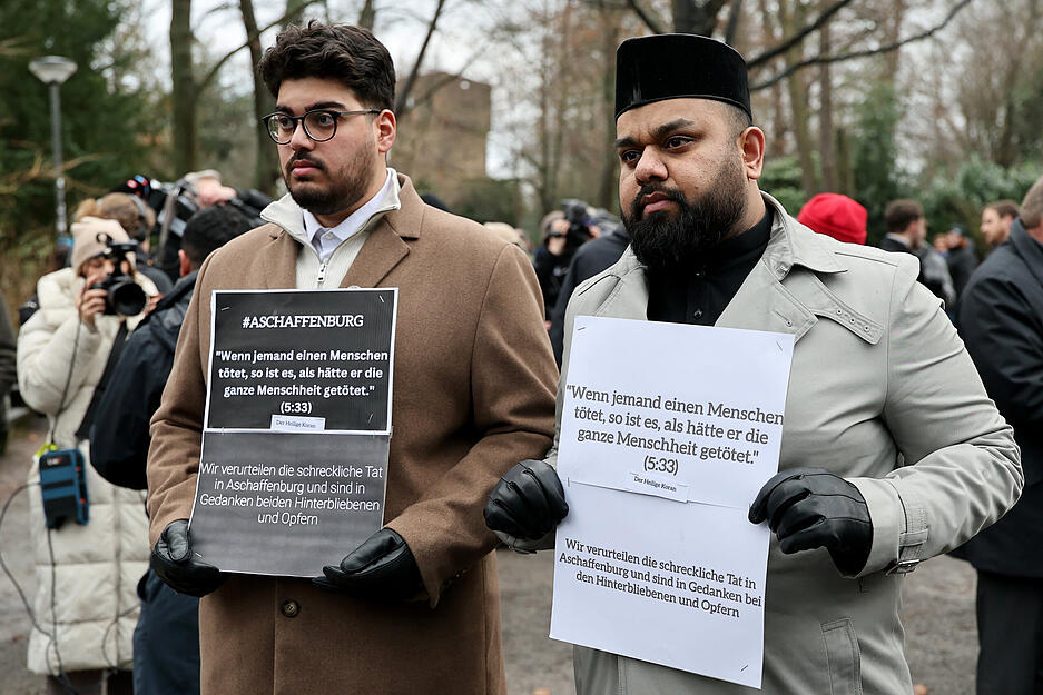 Zischan Mehmood (r), Imam von Aschaffenburg, und der gleichnamige Zischan Mehmood (l), Mitglied der Gemeinde, stehen mit Trauerbekundungen nach einer Kranzniederlegung nach dem tödlichen Angriff in einem Park.