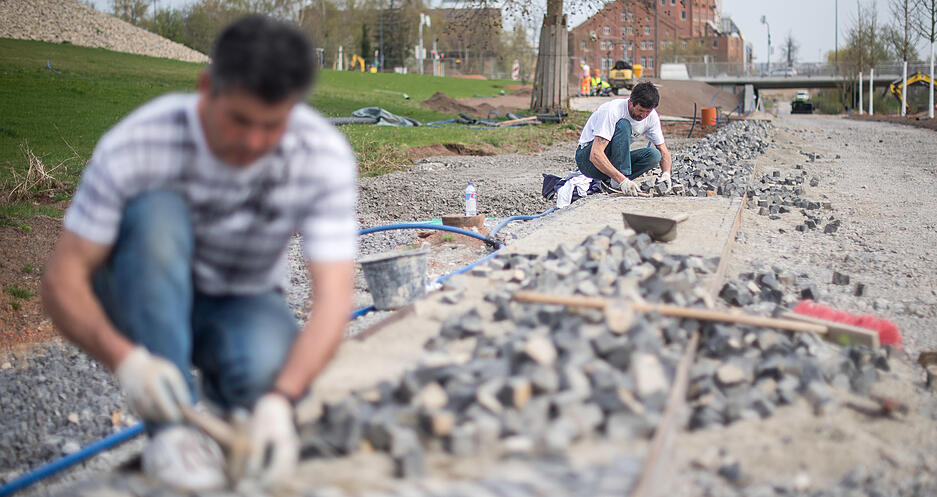 Arbeiter pflastern auf dem Gelände der Bundesgartenschau, die 2019 in Heilbronn stattfindet, einen Weg.