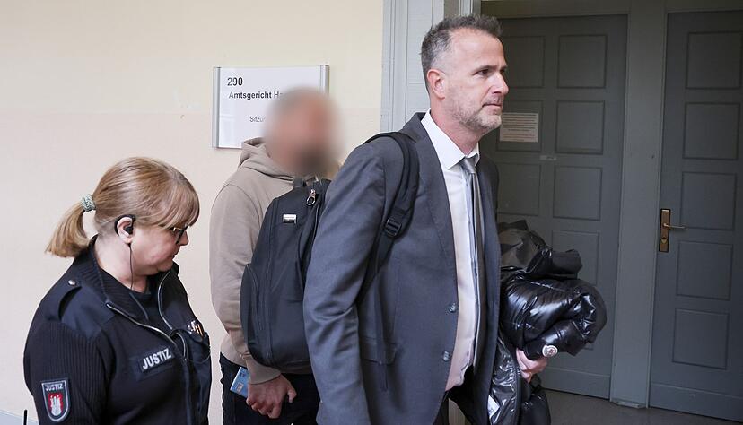 Der Zeuge (Mitte des Bildes) wird von seinem Anwalt (rechts im Bild) in den Gerichtssaal begleitet.