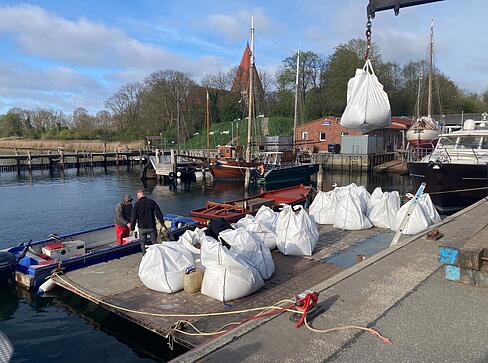 Gro&szlig;e Sands&auml;cke, sogenannte Big Bags, werden im Hafen von Kirchdorf auf Poel per Kran auf einen Ponton abgeladen.