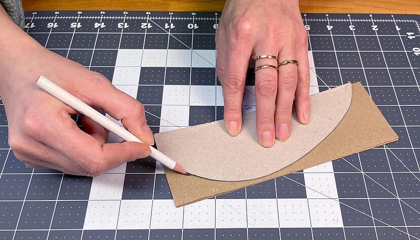 Zeichnen Sie eine halbe Ei-Form auf Karton vor und übertragen Sie diese insgesamt 12-mal auf Ihre Kraftpapierbögen. Zeichnen Sie eine halbe Ei-Form auf Karton vor und übertragen Sie diese insgesamt 12-mal auf Ihre Kraftpapierbögen.