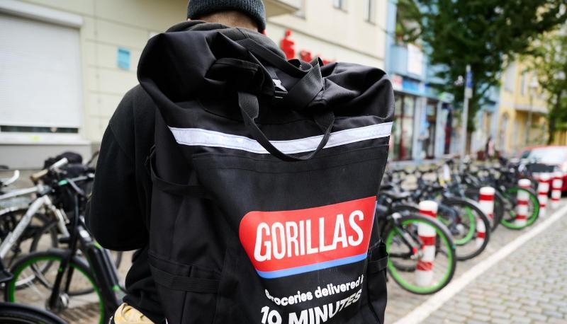 Ein Beschäftigter des Lieferdienstes Gorillas trägt einen Rucksack und steht vor den Fahrrädern. Ein Beschäftigter des Lieferdienstes Gorillas trägt einen Rucksack und steht vor den Fahrrädern.