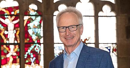 Christoph Baisch, hier vor einem Kunstfenster mit Reben-Kruzifix in der Kilianskirche, stellt sich auch unbequemen Fragen. Er ist überzeugt, ohne Kirche würde der Welt, der Gesellschaft und vielen Menschen etwas fehlen.
Foto: Andreas Veigel