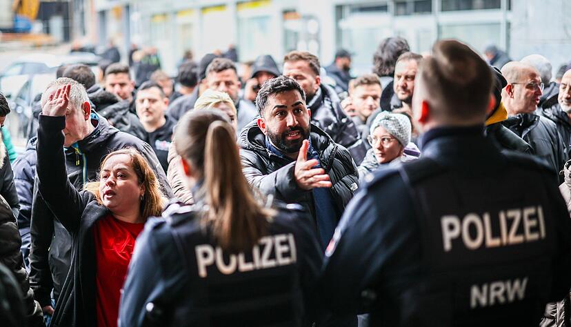Aufgebrachte Kunden diskutieren vor der Sparkassenfiliale in Buer mit Polizeibeamten nach der R&auml;umung des Vorraums der Filiale.