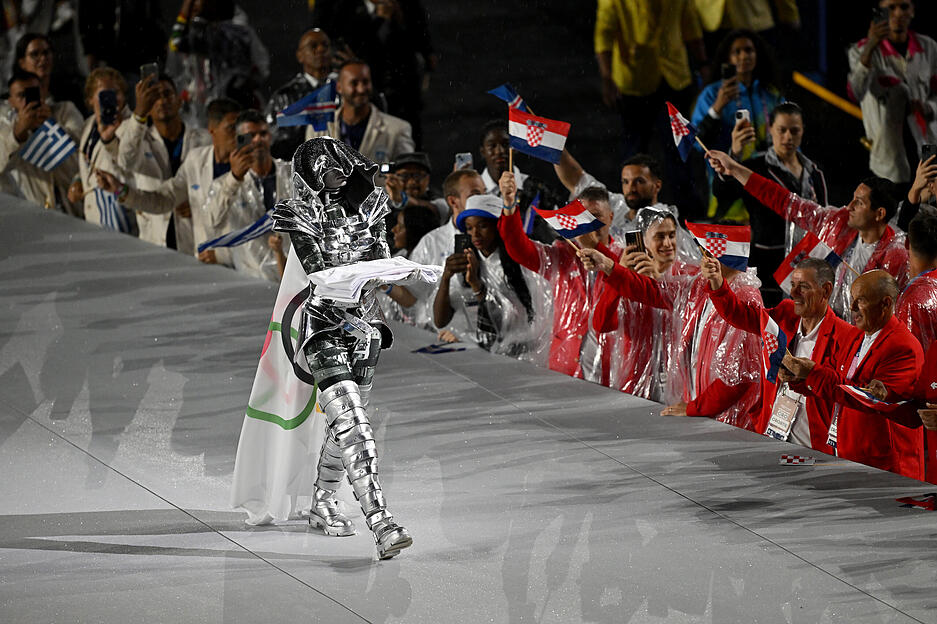 Ein Darsteller trägt die olympische Fahne ins Trocadero-Stadion.