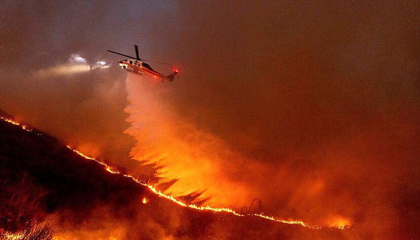 Ein Hubschrauber wirft Wasser &uuml;ber dem &laquo;Kenneth Fire&raquo; ab.