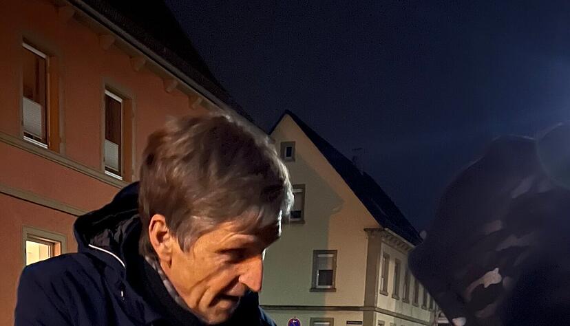 Roy Jastrow bringt einem Mann aus Nigeria ein Kirschkernsäckchen und erklärt ihm, wie er es anwenden kann.