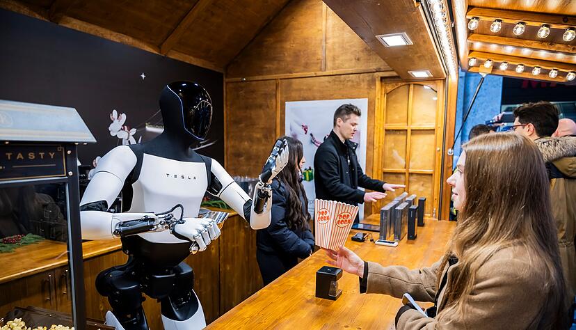 Der humanoide Roboter &laquo;Optimus&raquo; von Tesla verteilt bei seiner Vorstellung in der Mall of Berlin Popcorn an eine Besucherin.
